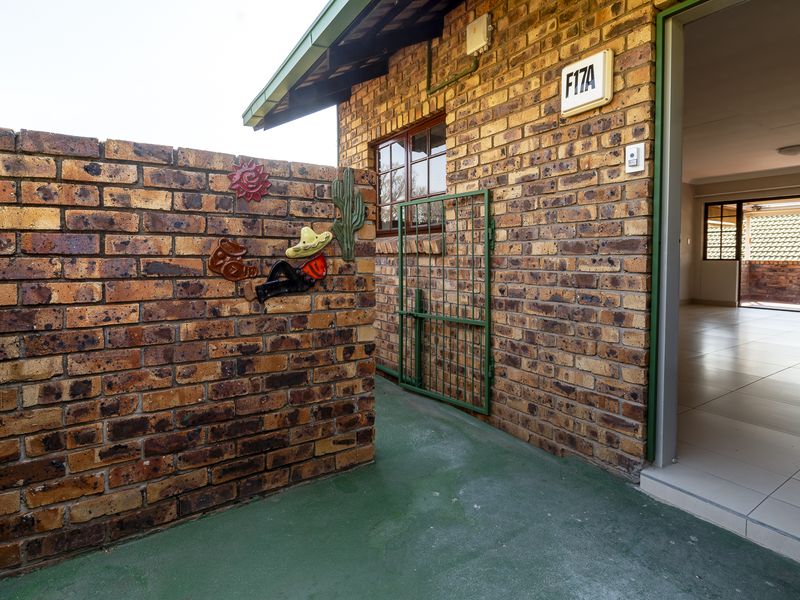 Entrance area of the flat featuring face brick exterior walls, a security gate, and tiled flooring leading into the interior living space.