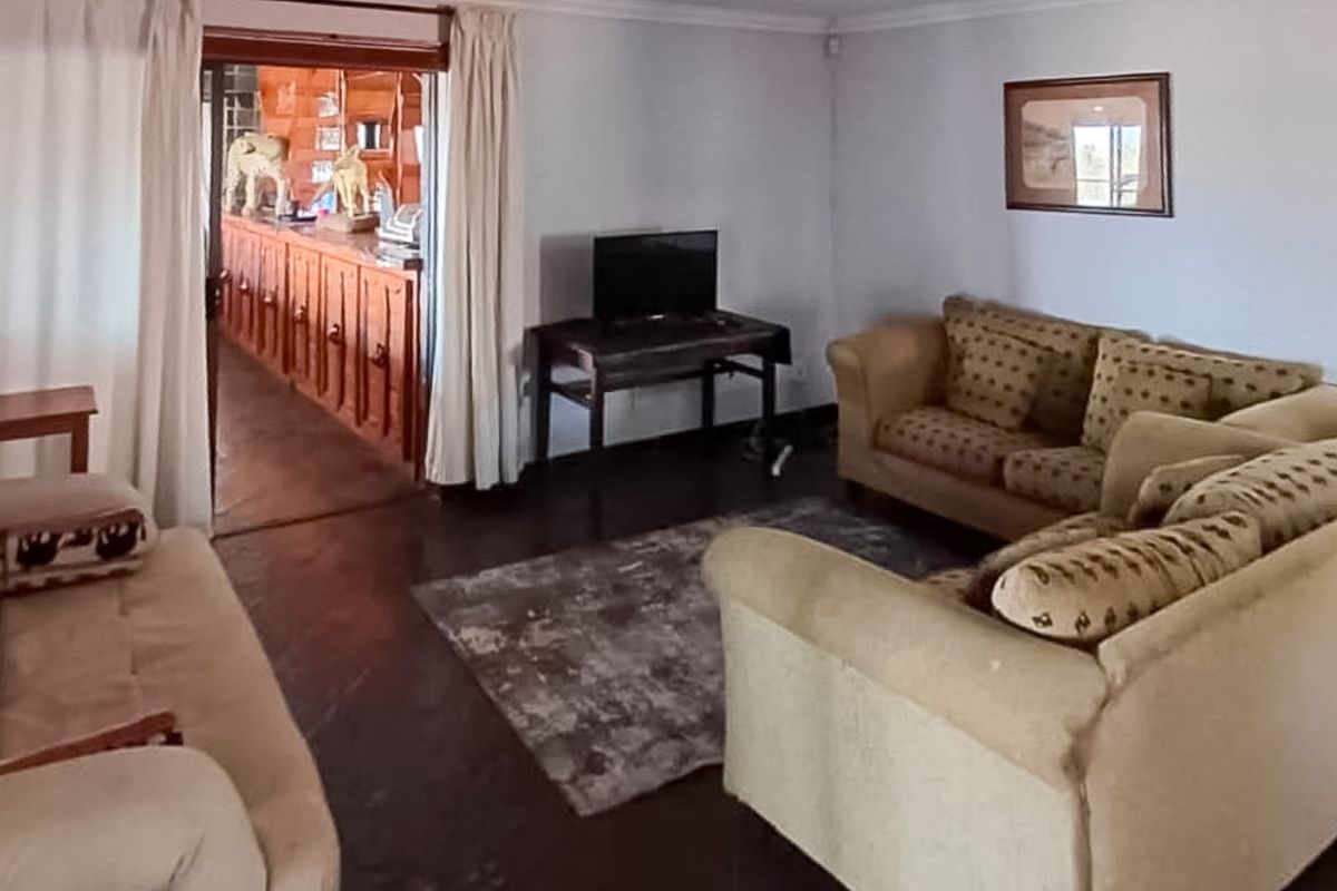 A living room area featuring tiled flooring and coved ceilings, with an open transition into an adjacent room with wooden cabinetry.