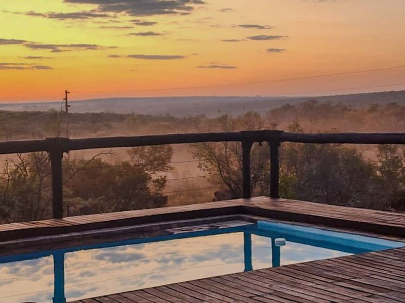 A raised timber deck featuring a swimming pool overlooking a scenic landscape at sunset.