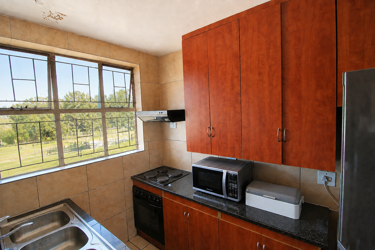 A functional kitchen featuring wood-finish cabinetry, granite countertops, a double basin sink, and built-in cooking appliances with large windows providing natural light.