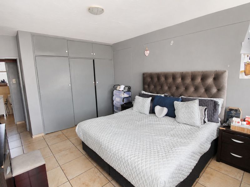 A bedroom featuring built-in cupboards, tiled flooring, and direct access to an en-suite bathroom area.