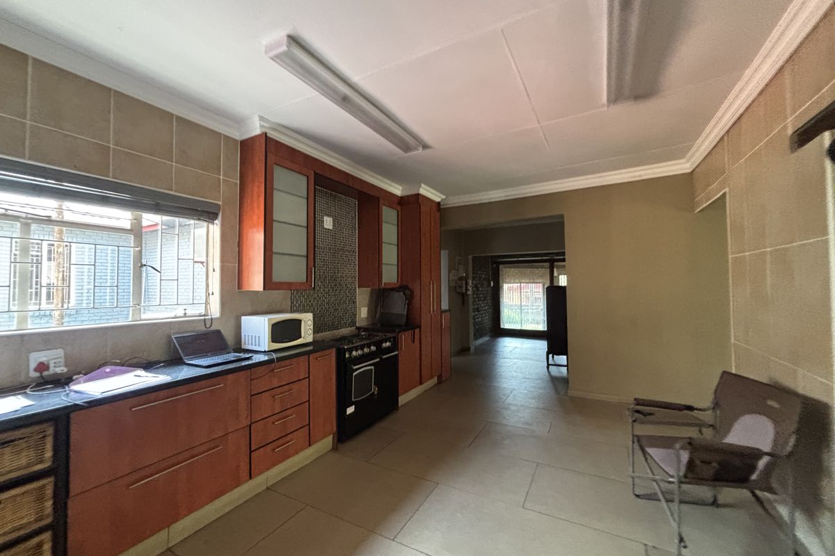 A functional kitchen featuring wooden cabinetry, granite countertops, a built-in oven, and tiled flooring, offering a practical layout with direct access to adjacent living areas.