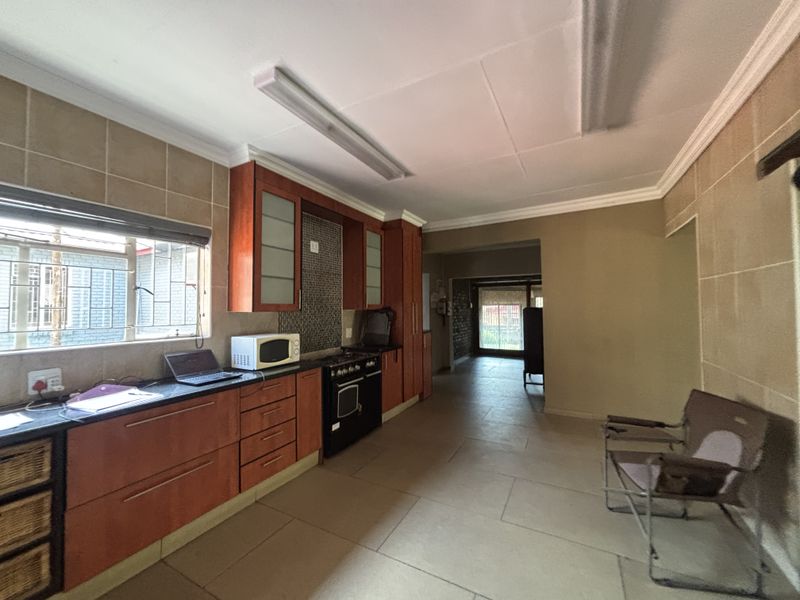 A functional kitchen featuring wooden cabinetry, granite countertops, a built-in oven, and tiled flooring, offering a practical layout with direct access to adjacent living areas.