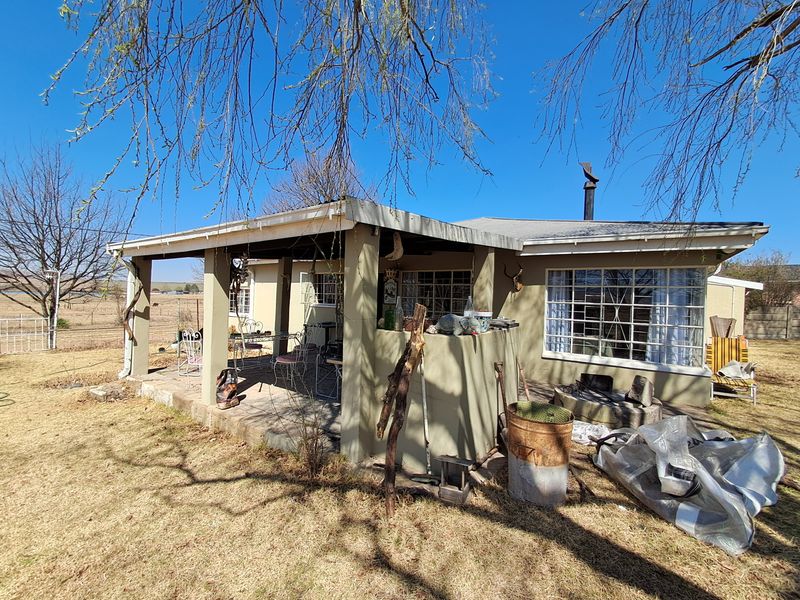 Rear view of the house featuring a covered patio area with concrete pillars and metal security bars on the windows.