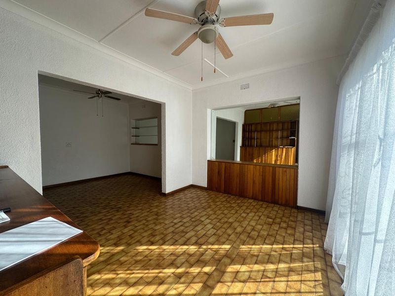 Spacious living area featuring tiled flooring, a ceiling fan, and built-in wooden cabinetry, offering a versatile layout with an open-plan feel.