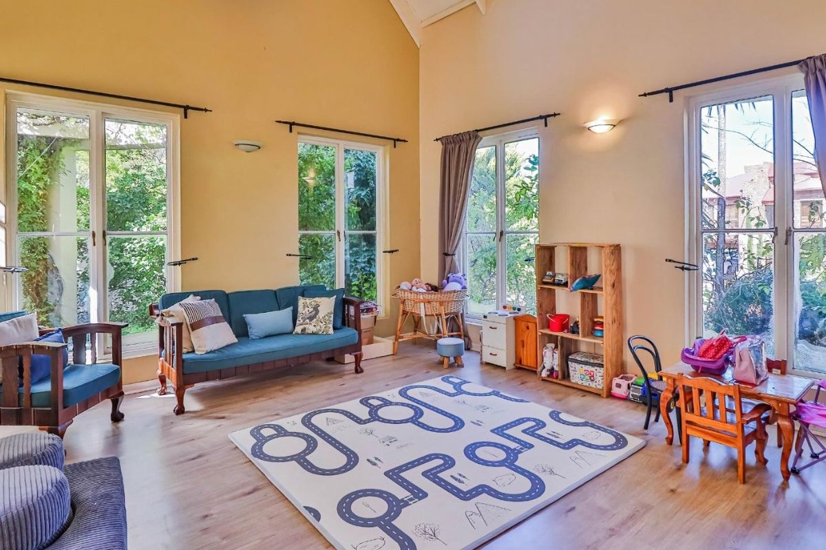 Spacious living room featuring vaulted ceilings, light laminate flooring, and multiple sets of French doors providing abundant natural light and garden views.