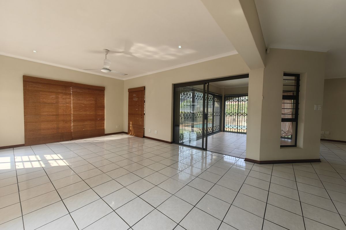 Spacious, light-filled living area featuring neutral tiled flooring, recessed lighting, and large sliding doors providing seamless access to the outdoor patio.