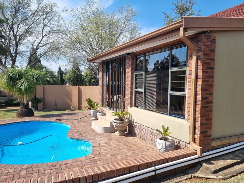 Outdoor pool area featuring brick paving, a swimming pool, and a brick-clad building exterior with aluminium window frames and security gates.