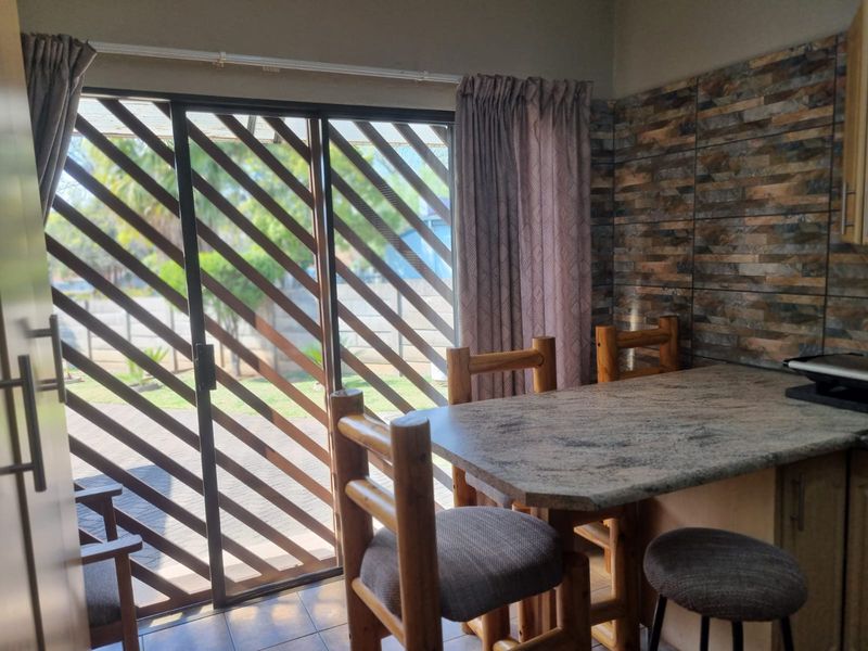 Kitchen area featuring a granite breakfast bar, stone-cladding wall finish, and a sliding glass door providing direct access to the outdoor patio.