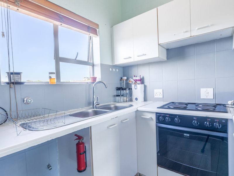 A functional kitchen featuring white cabinetry, laminate countertops, a double bowl sink, and a built-in electric oven with a hob.