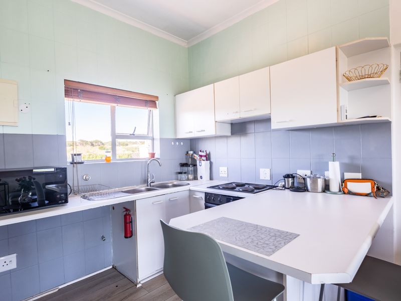 A functional kitchen featuring built-in cabinetry, a tiled splashback, integrated hob and oven, and a breakfast counter area.