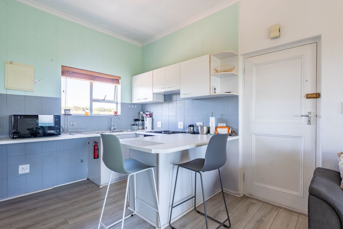 Compact kitchen featuring built-in cabinetry, laminate countertops, an electric hob, and a tiled backsplash, offering a functional layout for daily meal preparation.