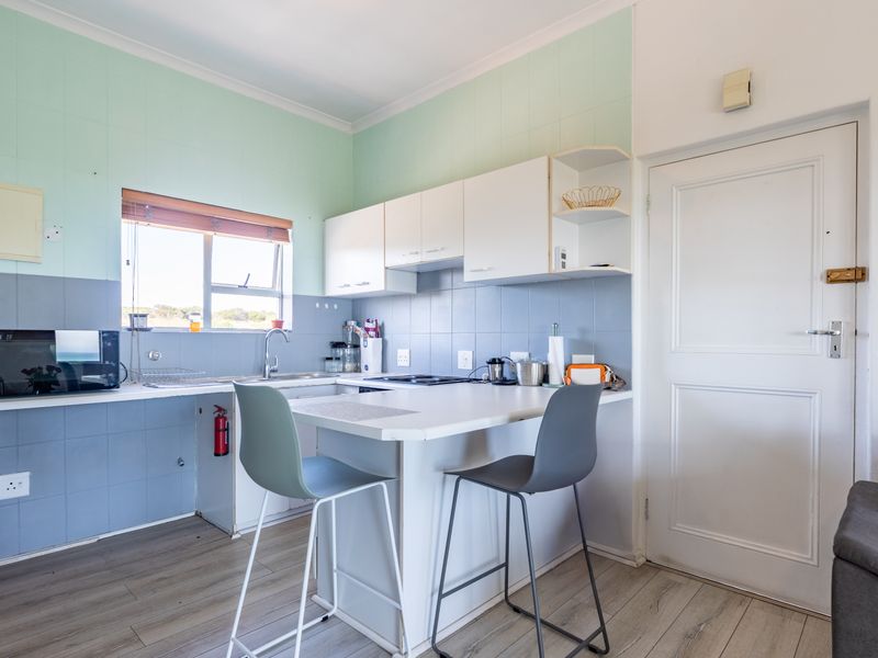 Compact kitchen featuring built-in cabinetry, laminate countertops, an electric hob, and a tiled backsplash, offering a functional layout for daily meal preparation.