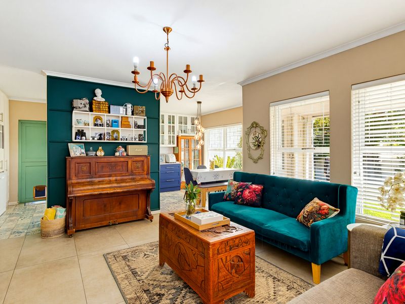 An open-plan living and dining area featuring tiled floors, decorative wall paneling, and a combination of chandelier and pendant lighting.