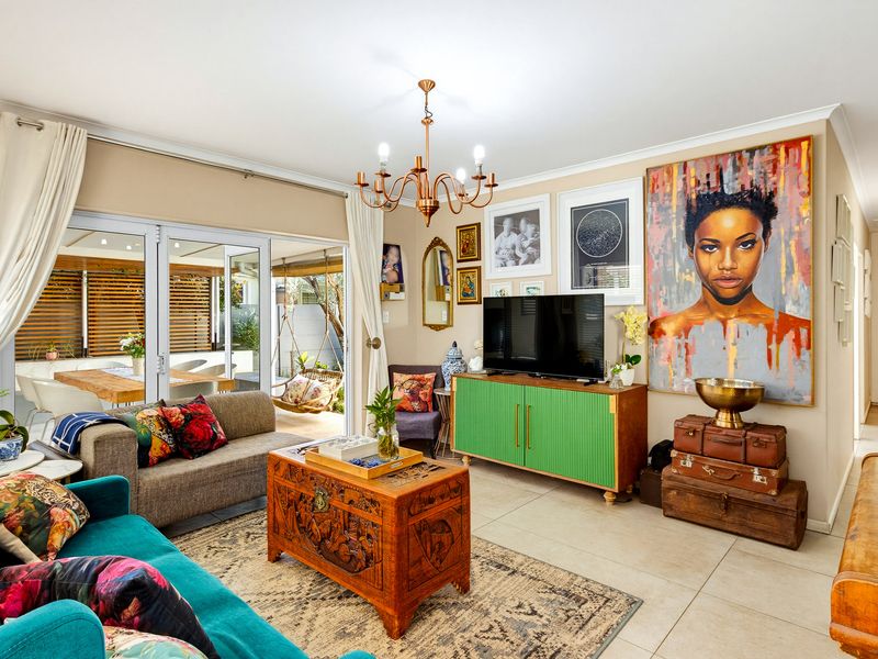 A bright and inviting living room featuring tiled flooring, a central chandelier, and large sliding glass doors that provide seamless access to the outdoor patio.