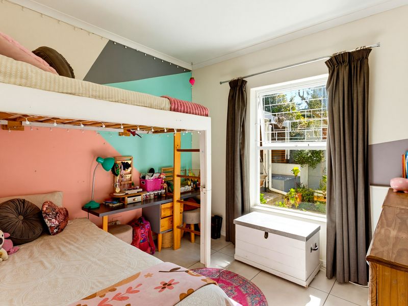 A bedroom featuring tiled flooring and a window with security bars, currently utilized as a child's room with a bunk bed setup.