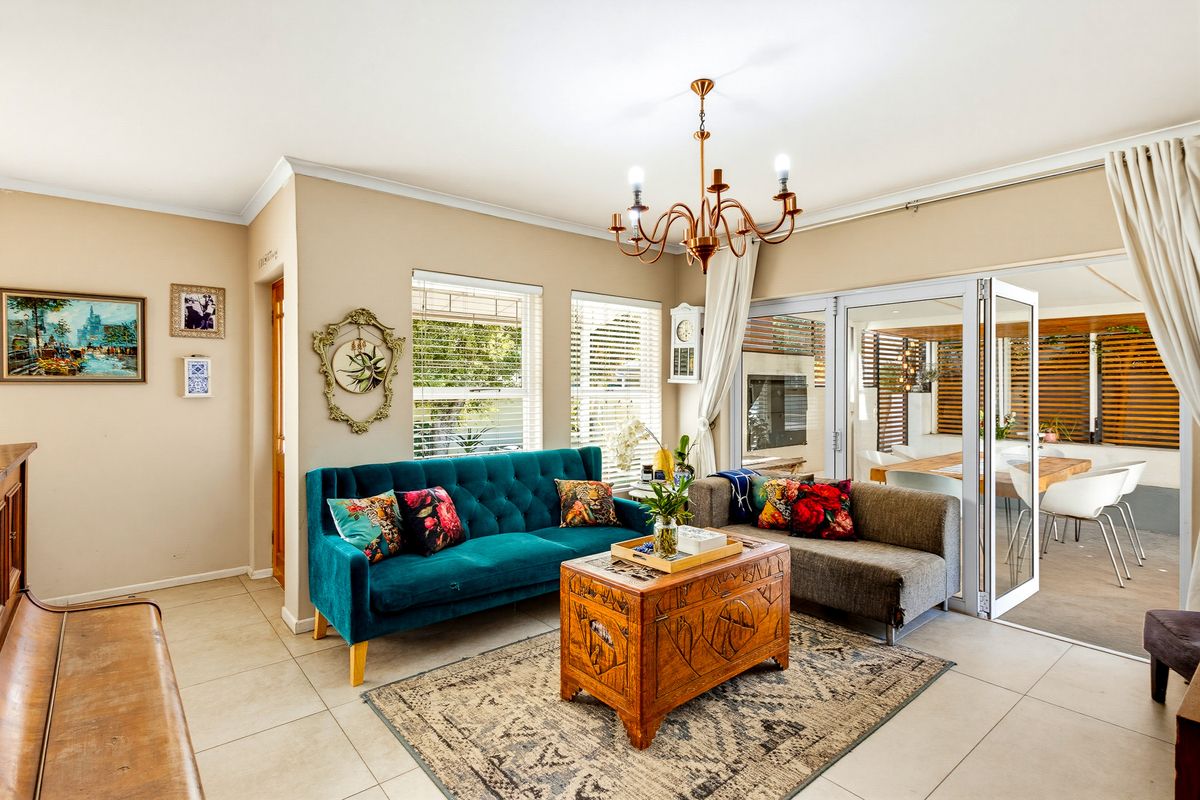 A bright living room featuring tiled flooring, a classic chandelier, and large sliding glass doors that provide seamless access to the outdoor patio area.