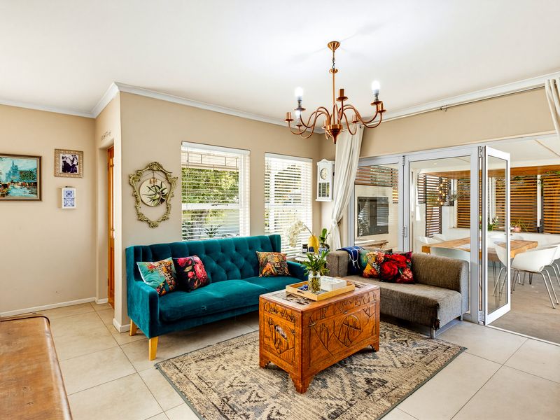 A bright living room featuring tiled flooring, a classic chandelier, and large sliding glass doors that provide seamless access to the outdoor patio area.