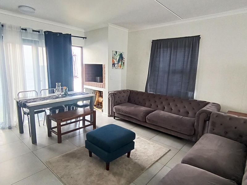 Spacious open-plan living and dining area featuring tiled flooring, a built-in brick fireplace, and large sliding glass doors providing access to the exterior.