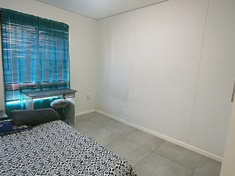 A bedroom featuring tiled flooring and a built-in cupboard, requiring minor cosmetic attention to the walls.