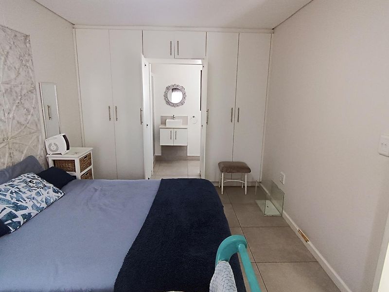 Spacious bedroom featuring extensive built-in cupboards, neutral tiled flooring, and direct access to an en-suite bathroom.