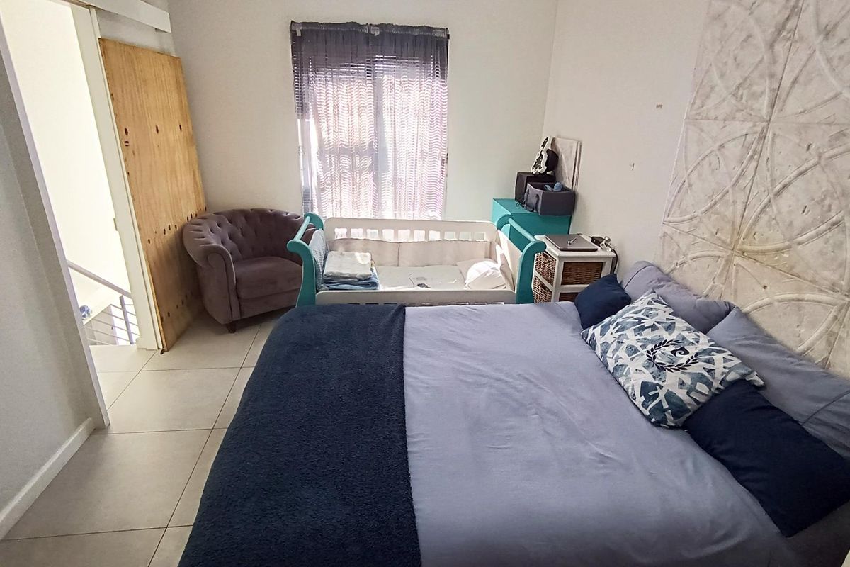 A bedroom featuring tiled flooring and a decorative wall panel feature, currently utilized as a nursery and sleeping space.