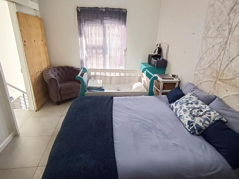 A bedroom featuring tiled flooring and a decorative wall panel feature, currently utilized as a nursery and sleeping space.
