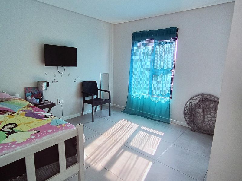 A bedroom featuring tiled flooring and a window with fitted blinds, providing natural light.