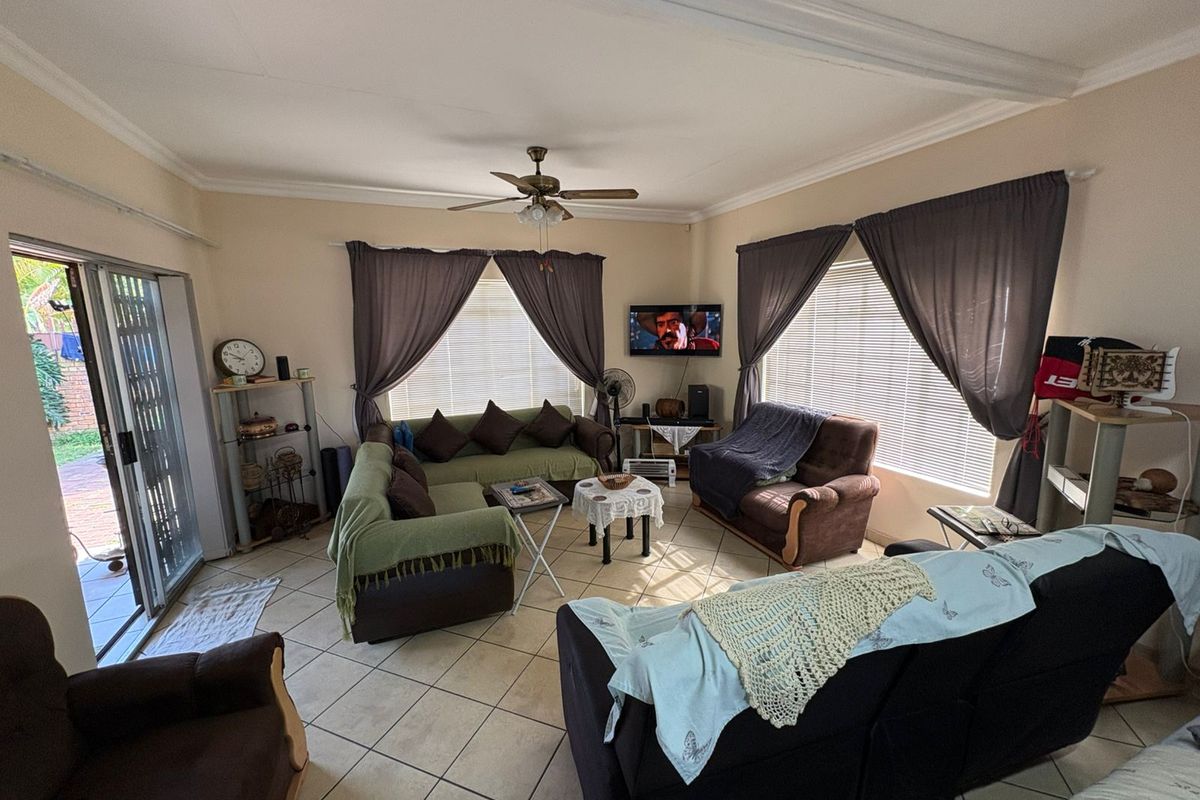 Spacious living room featuring tiled flooring, a ceiling fan, and large sliding glass doors providing access to the outdoor area.