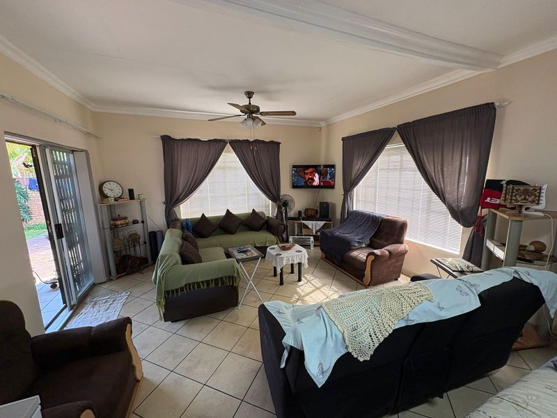 Spacious living room featuring tiled flooring, a ceiling fan, and large sliding glass doors providing access to the outdoor area.