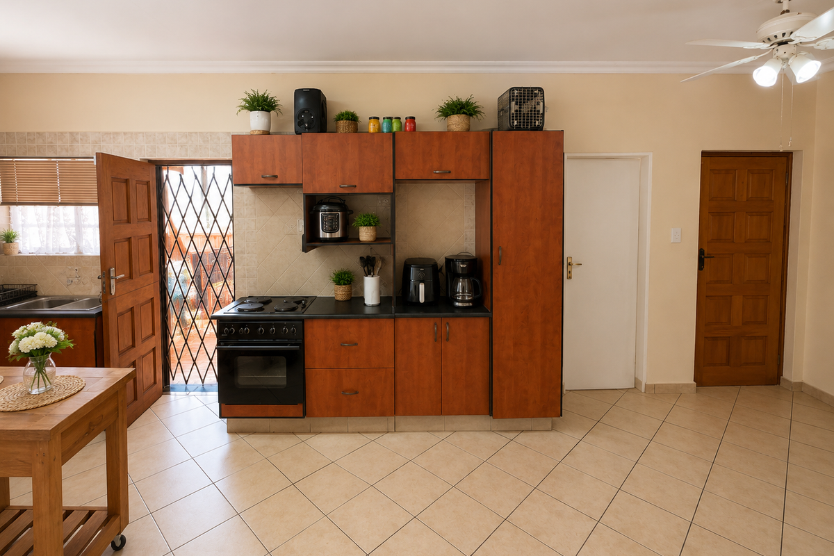 A functional kitchen area featuring built-in wooden cabinetry, an integrated electric stove and oven, tiled flooring, and direct access to an outdoor space.