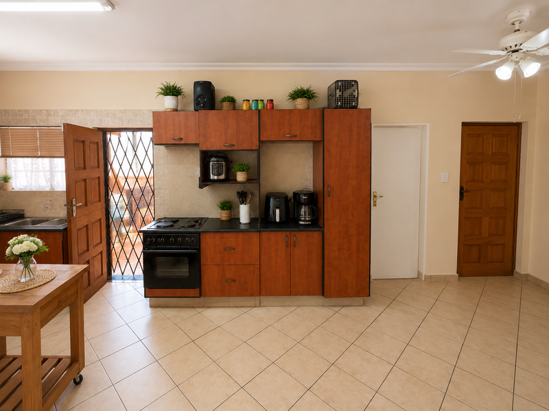 A functional kitchen area featuring built-in wooden cabinetry, an integrated electric stove and oven, tiled flooring, and direct access to an outdoor space.