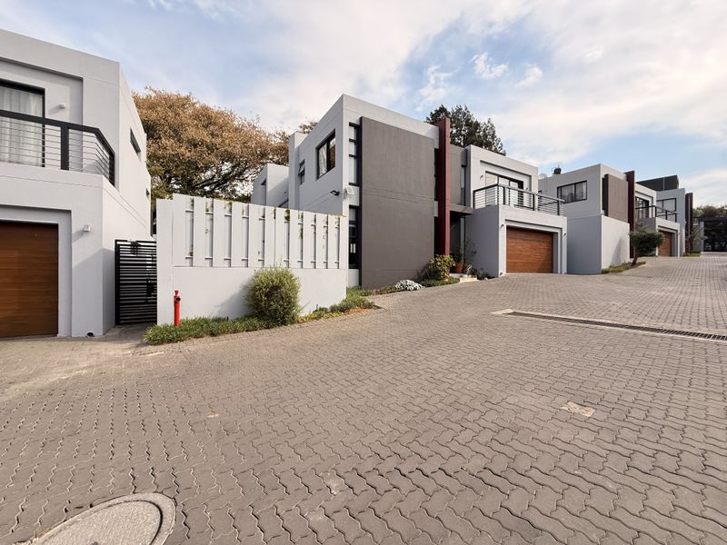 Modern residential complex featuring paved driveway access, contemporary multi-level facades with integrated garages, and private balconies.