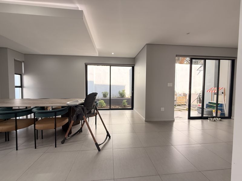 Spacious open-plan living area featuring modern tiled flooring, recessed ceiling details, and large sliding glass doors providing access to the outdoor patio.