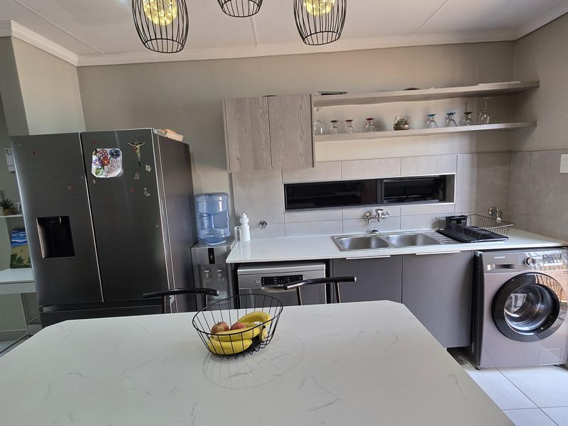 Modern kitchen featuring a central island with quartz countertops, sleek cabinetry, open shelving, and contemporary pendant lighting.
