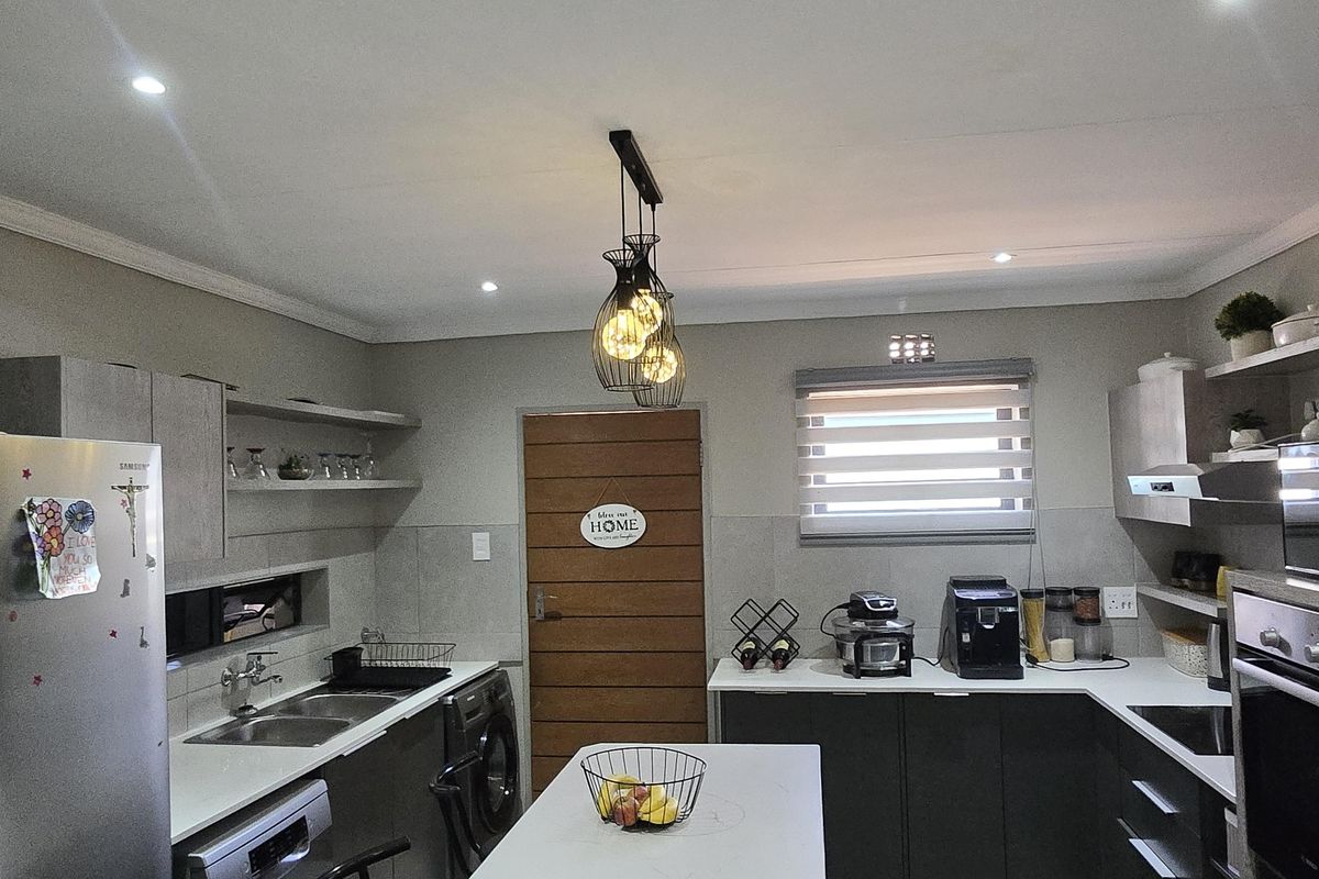 Modern kitchen featuring a central island, sleek cabinetry, built-in oven, double sink, and tiled flooring with recessed lighting.