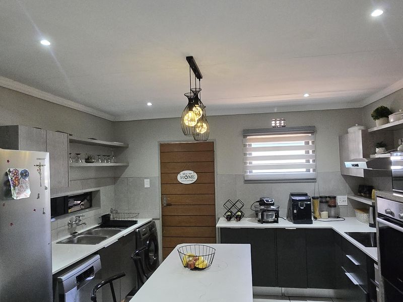 Modern kitchen featuring a central island, sleek cabinetry, built-in oven, double sink, and tiled flooring with recessed lighting.