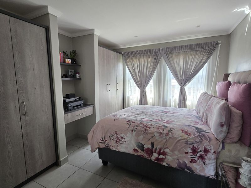 A well-maintained bedroom featuring built-in cupboards, a integrated desk area, tiled flooring, and recessed ceiling lighting.