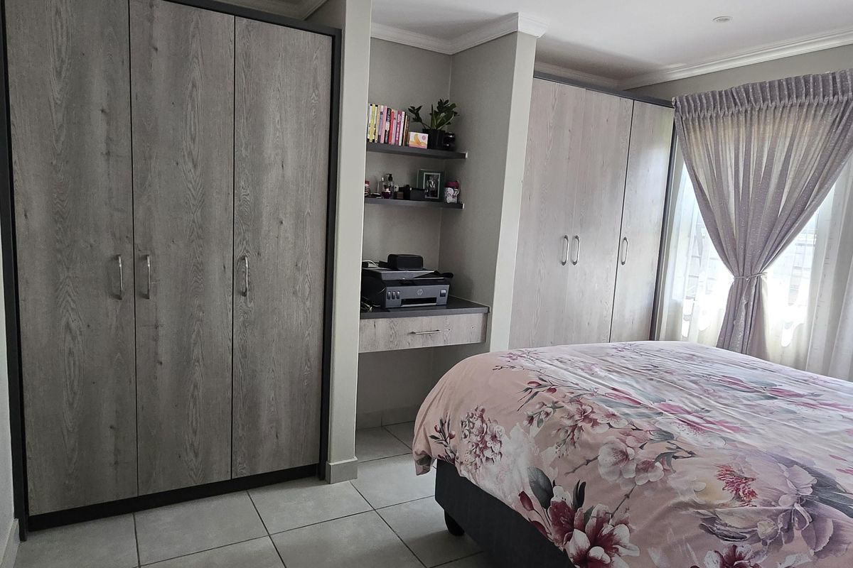 A well-maintained bedroom featuring extensive built-in cupboards, a integrated desk area, tiled flooring, and recessed ceiling lighting.