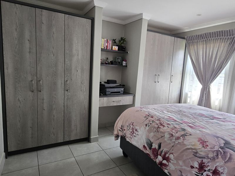 A well-maintained bedroom featuring extensive built-in cupboards, a integrated desk area, tiled flooring, and recessed ceiling lighting.