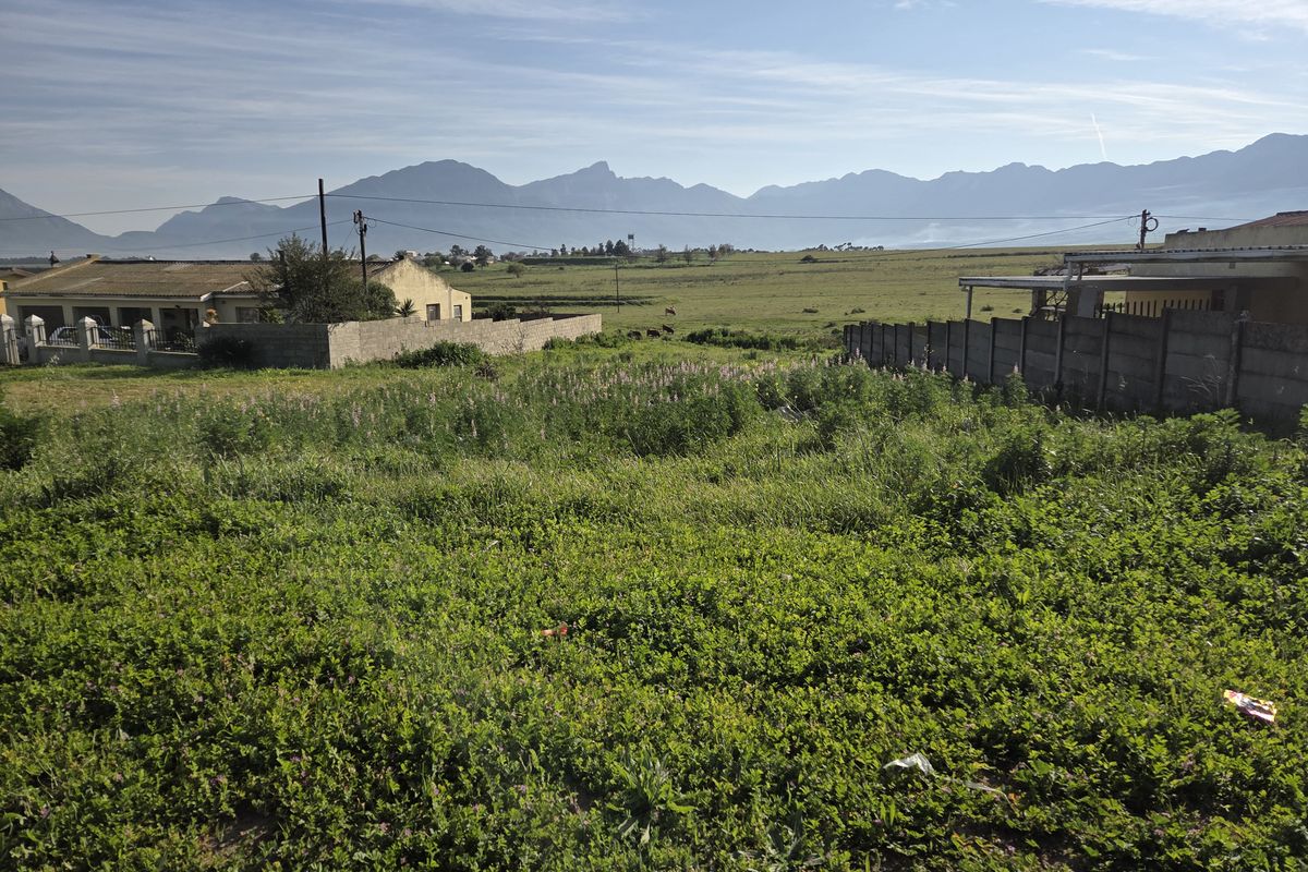 A vacant residential plot featuring expansive mountain views and surrounding boundary walls, offering a scenic outlook for potential development.