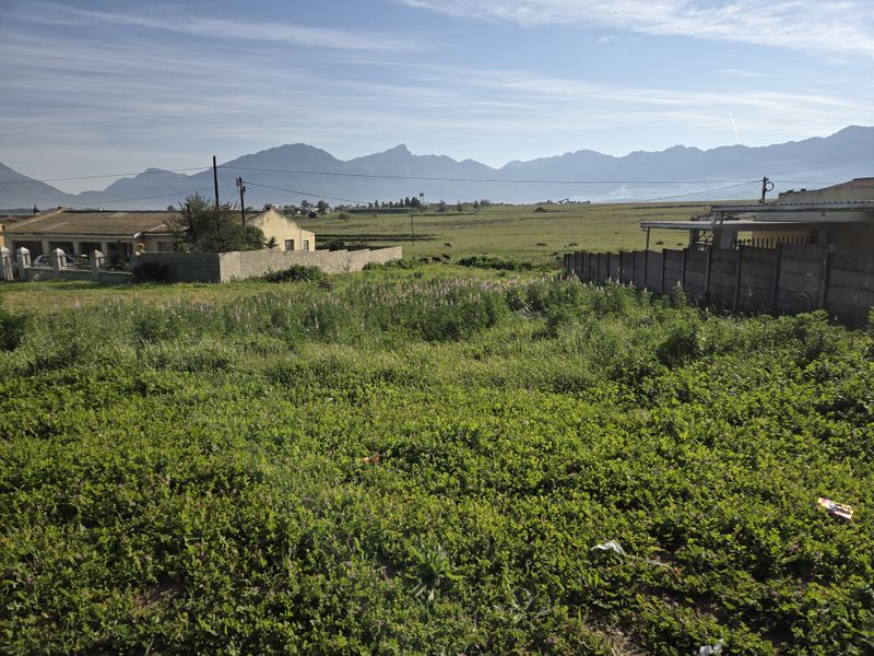 A vacant residential plot featuring expansive mountain views and surrounding boundary walls, offering a scenic outlook for potential development.
