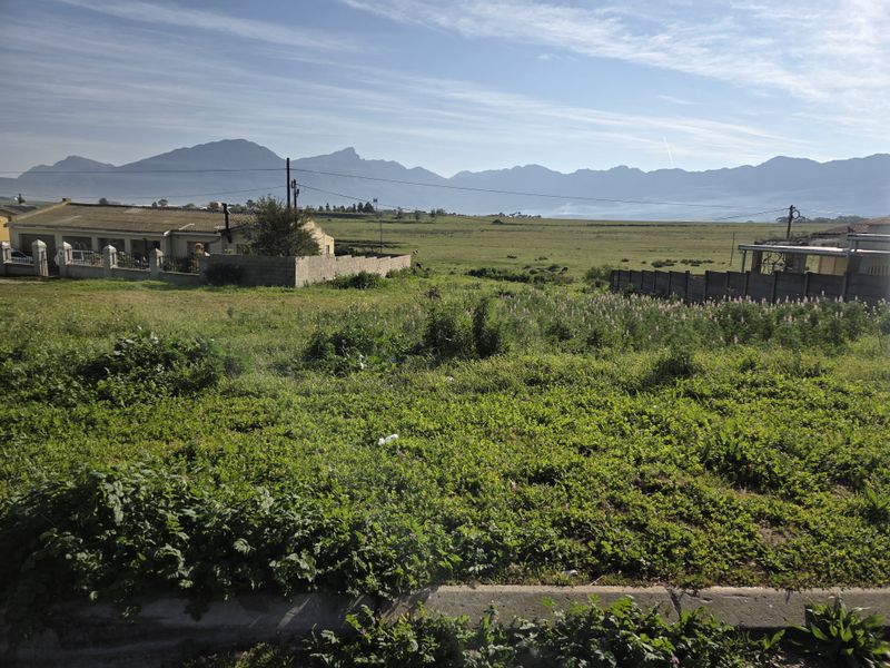 A vacant residential plot featuring expansive mountain views and established boundary walls, offering a scenic outlook in a quiet neighborhood setting.