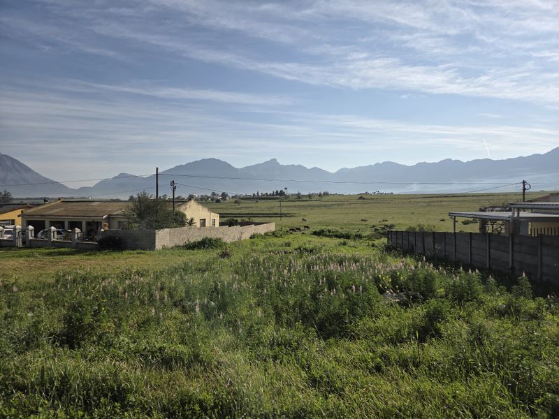 A scenic view of open residential land featuring surrounding mountain vistas and existing boundary walls.