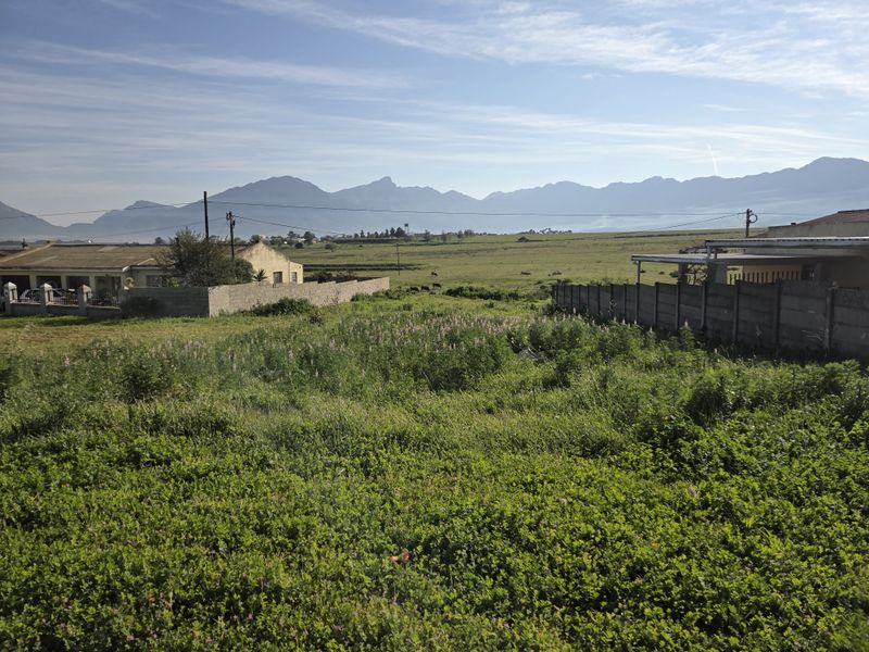 A view of a vacant residential plot featuring surrounding boundary walls and scenic mountain vistas in the background.