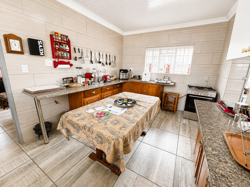 A functional kitchen featuring tiled walls and floors, granite countertops, built-in wooden cabinetry, and a gas stove with oven.