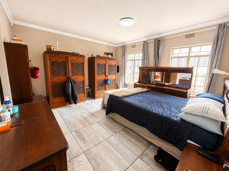 Spacious bedroom featuring tiled flooring, crown molding, and large windows that provide ample natural light.