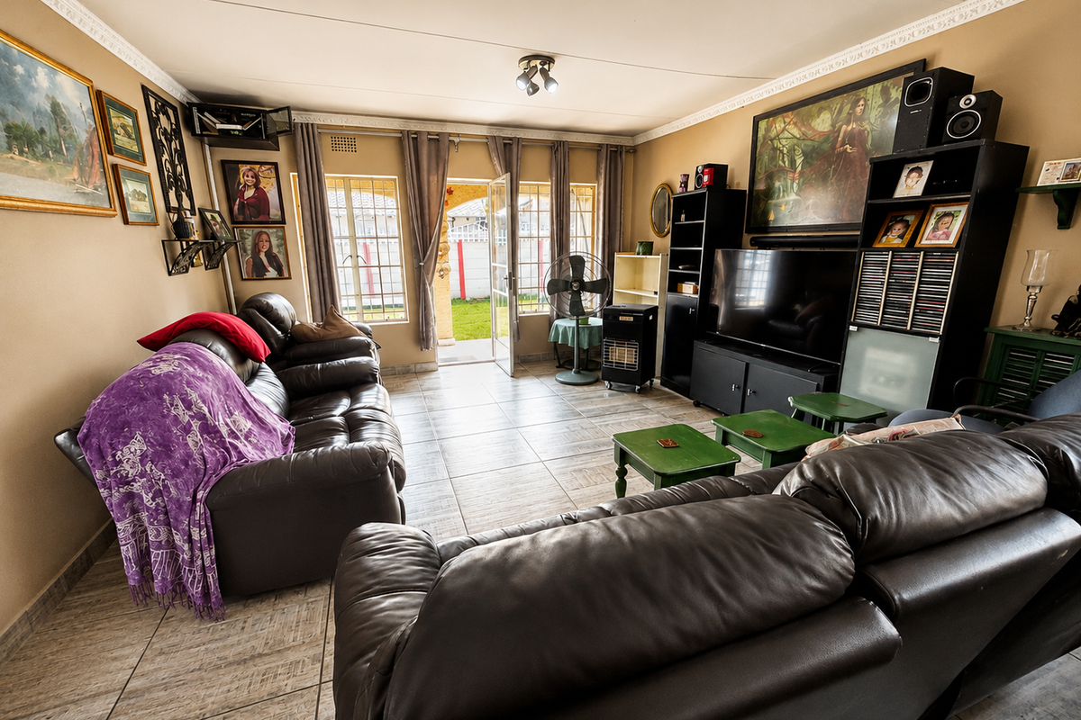 A comfortable living room featuring tiled flooring, decorative ceiling cornices, and direct access to the rear garden through a glass sliding door.