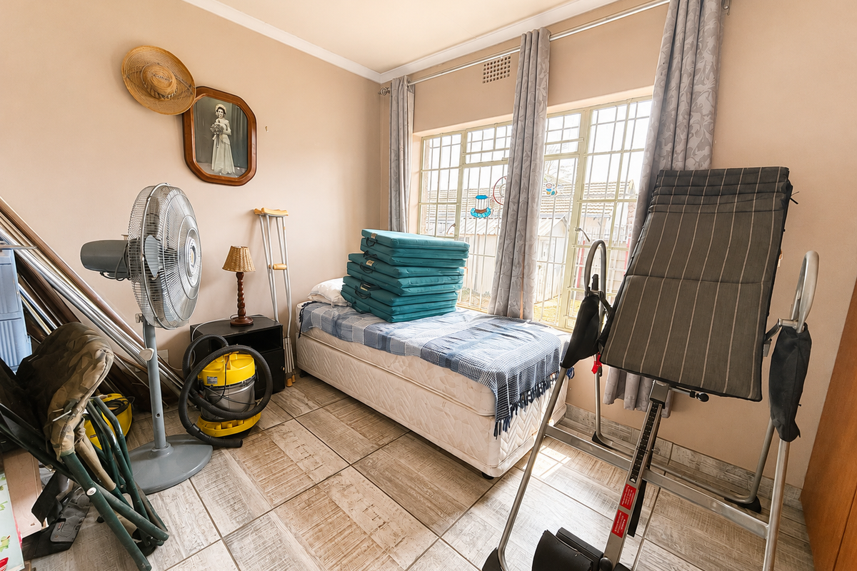 A bedroom featuring tiled flooring and large windows with security bars, providing natural light and ventilation.