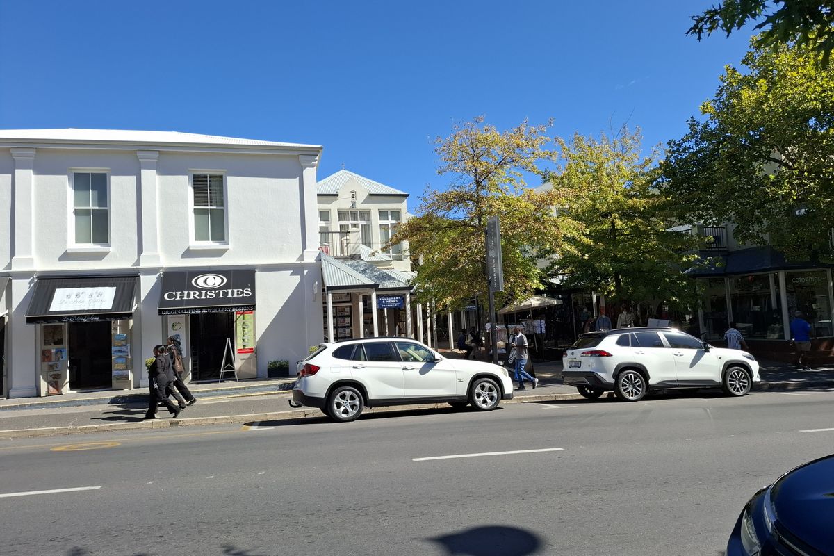 A street-level view of a commercial building facade with storefronts and awnings along a paved road.